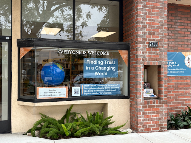 Reading room window display containing a spinning globe and posters advertising a public talk